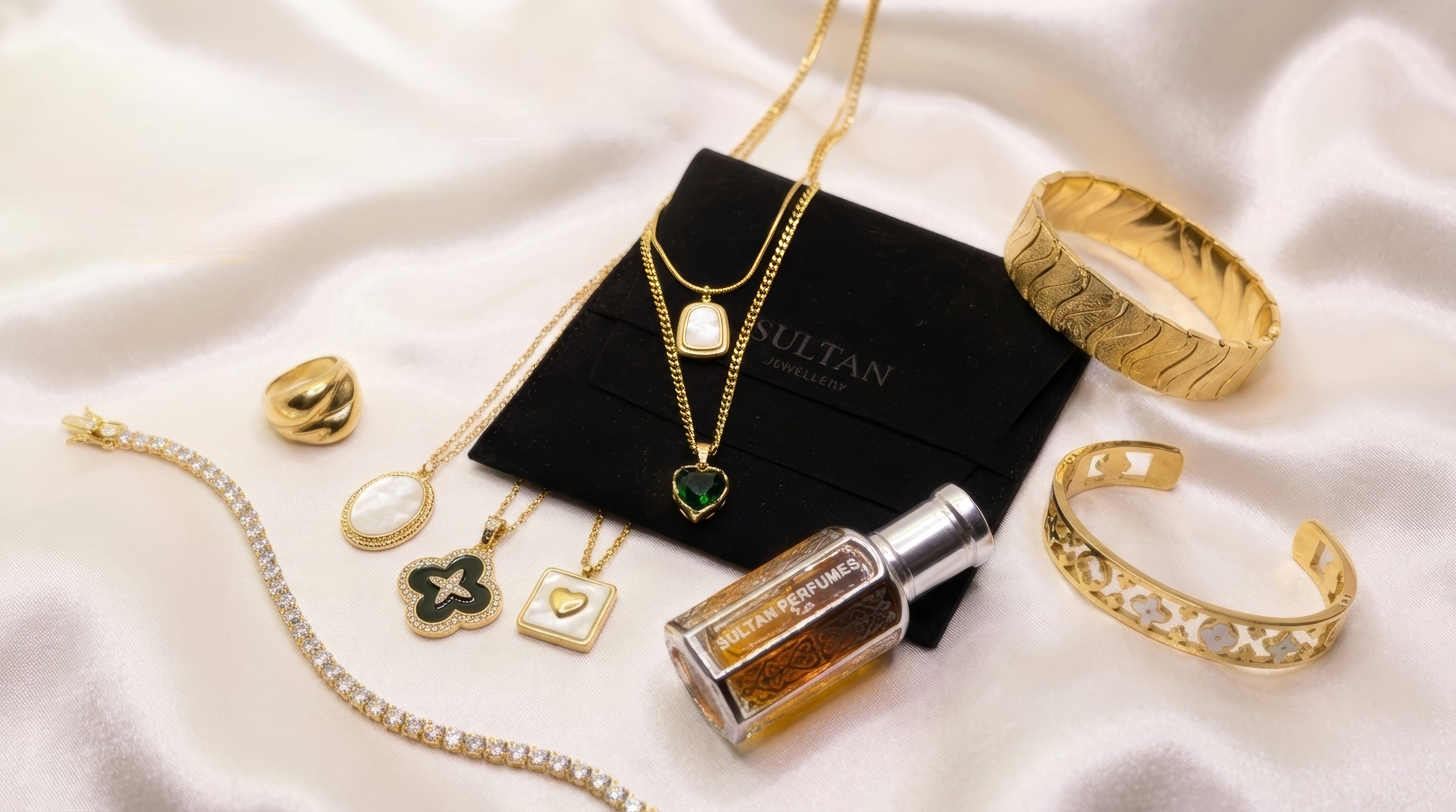 Gold jewelry including necklaces, bracelets, and a bottle on a white fabric background